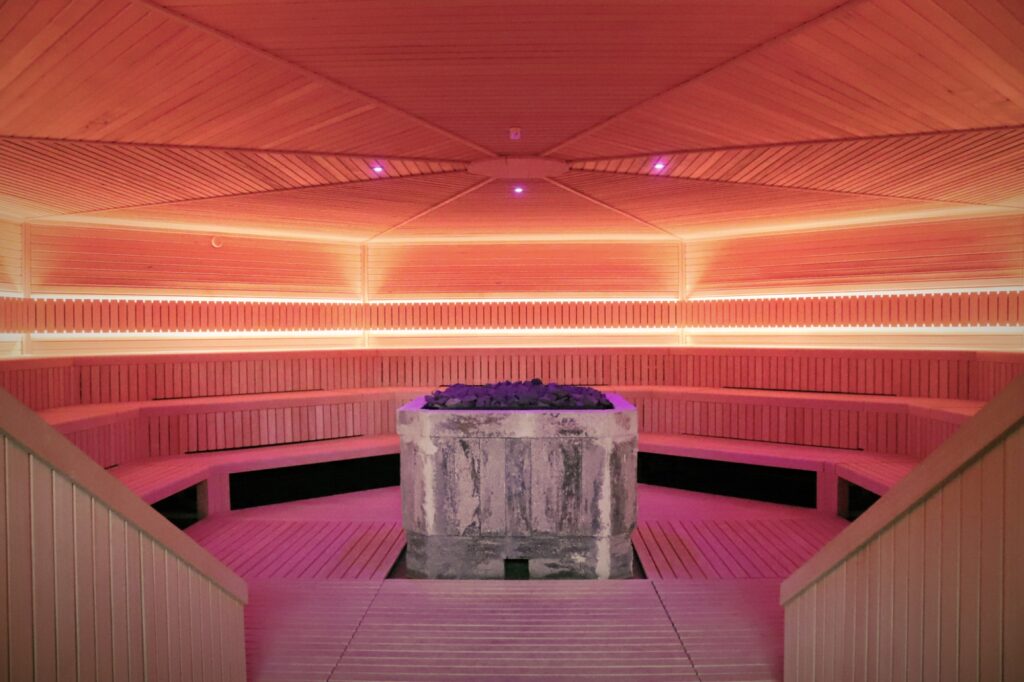 Opgietsauna met stenen kachelblok roze licht in Huize Holterhof